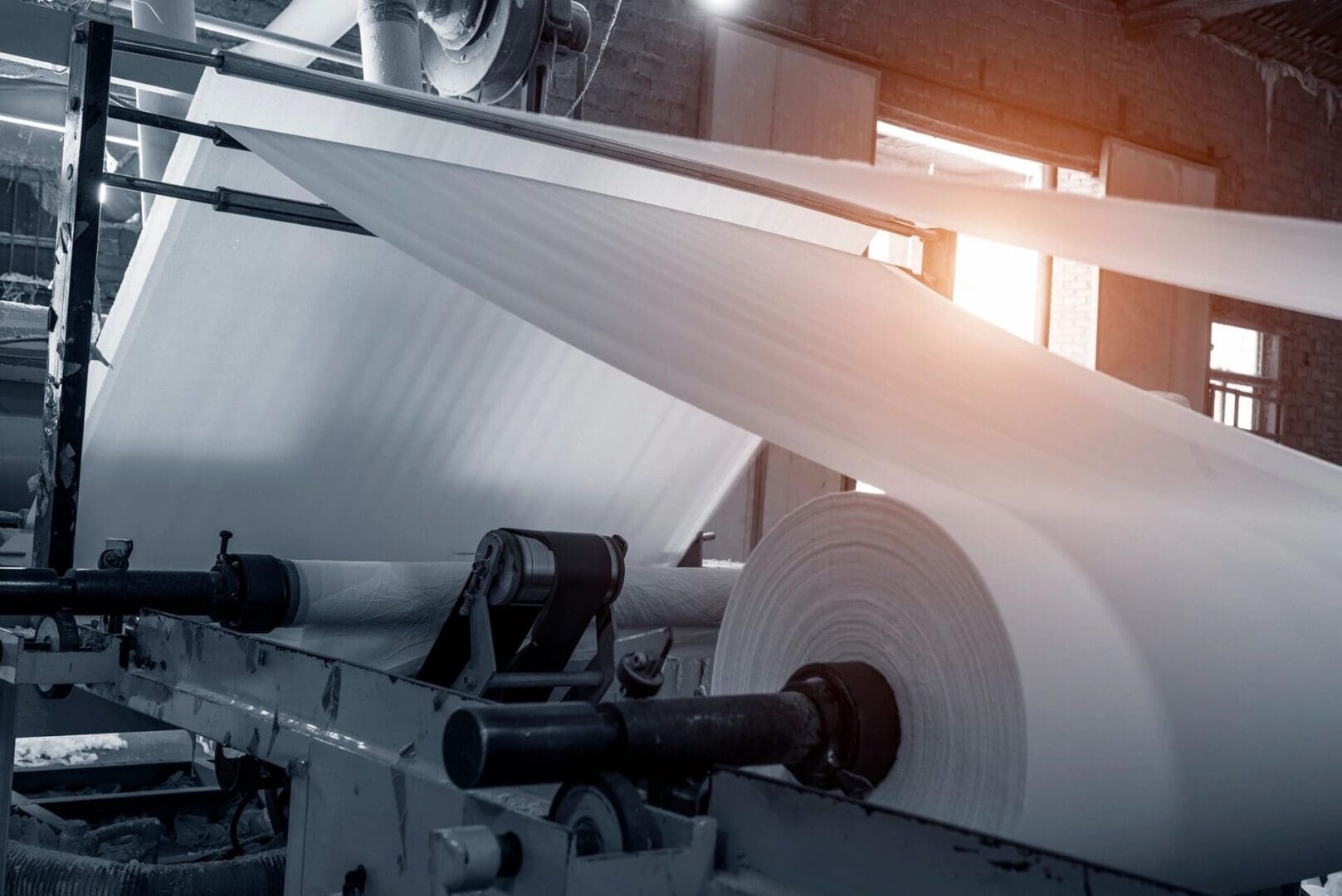 A machine that is rolling paper in the middle of a factory.